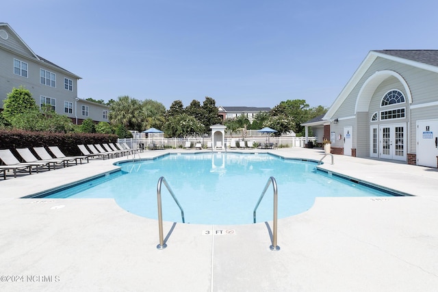 pool featuring french doors, a patio area, and fence