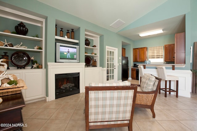 living room with built in shelves, light tile patterned floors, and vaulted ceiling