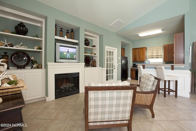 interior space with lofted ceiling, light tile patterned flooring, a fireplace, and built in features