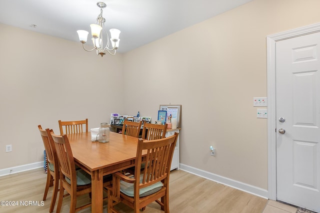 dining space featuring a chandelier, light wood-style flooring, and baseboards