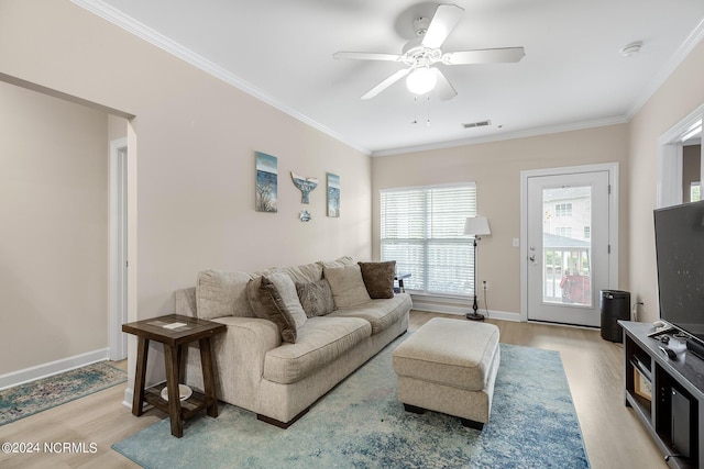 living room featuring baseboards, light wood finished floors, visible vents, and crown molding