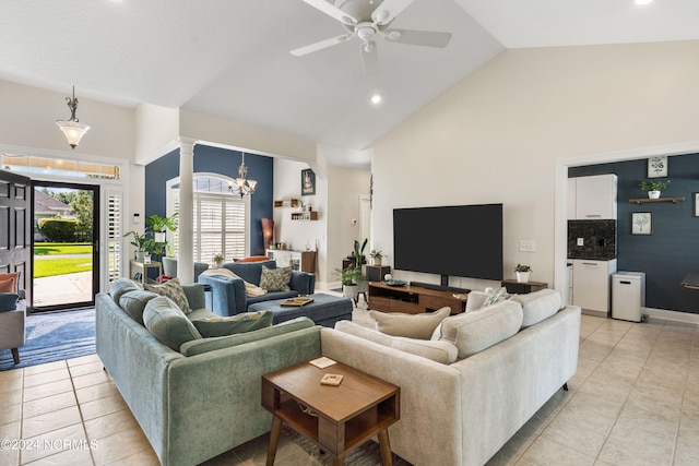 tiled living room with high vaulted ceiling and ceiling fan with notable chandelier