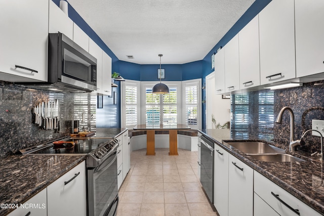 kitchen with backsplash, stainless steel appliances, light tile patterned flooring, and dark stone countertops