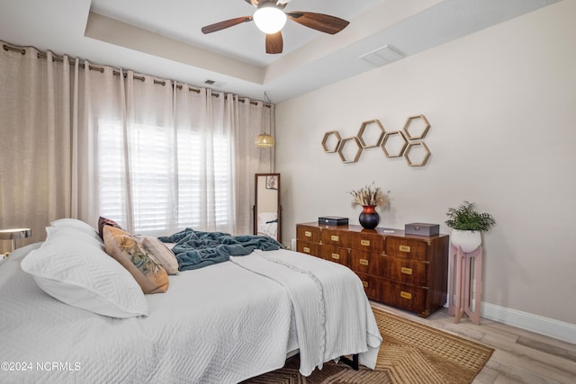 bedroom featuring ceiling fan, a raised ceiling, and hardwood / wood-style flooring