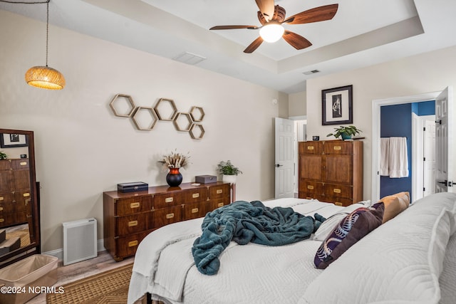 bedroom with ceiling fan and a raised ceiling