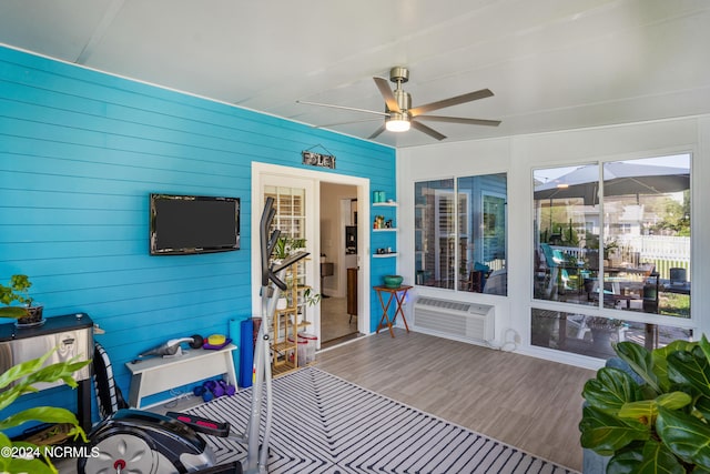 sunroom / solarium featuring ceiling fan, a healthy amount of sunlight, and a wall unit AC