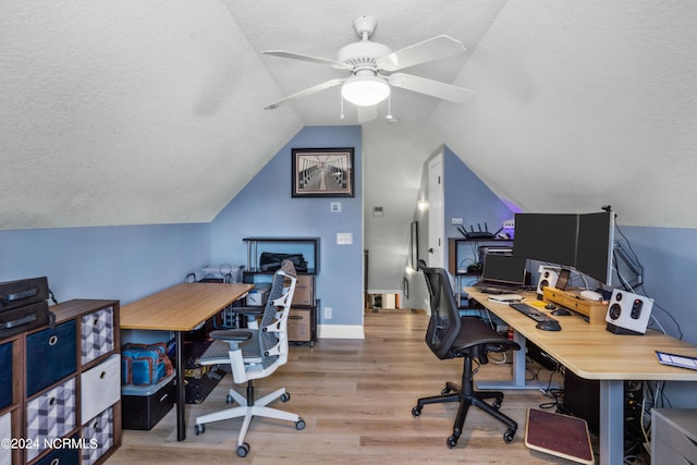 office area featuring ceiling fan, light wood-type flooring, vaulted ceiling, and a textured ceiling