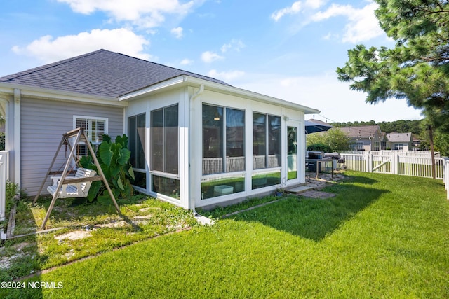 rear view of house with a sunroom and a lawn