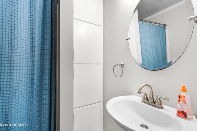 bathroom with a shower with curtain, ornamental molding, and sink