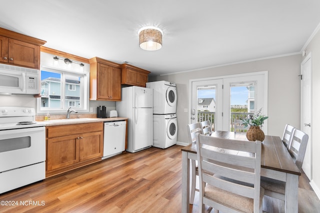 kitchen featuring sink, white appliances, light hardwood / wood-style flooring, stacked washer and clothes dryer, and ornamental molding