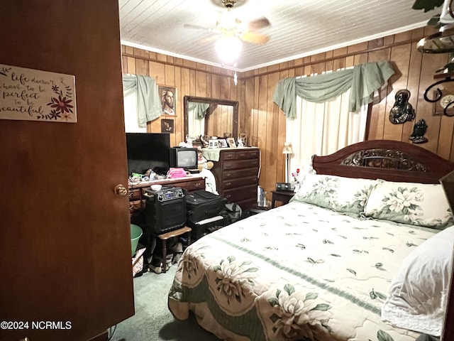 bedroom featuring crown molding, ceiling fan, wooden walls, and carpet floors