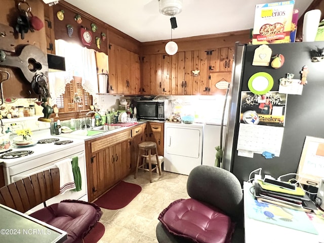 kitchen with white electric stove, washing machine and dryer, sink, and stainless steel refrigerator