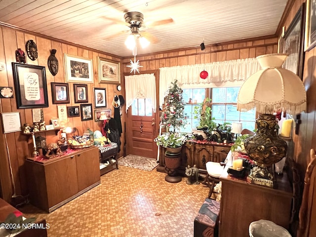 interior space featuring crown molding, wooden walls, and ceiling fan