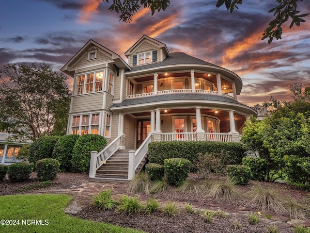 view of front of property featuring covered porch, a shingled roof, and a balcony