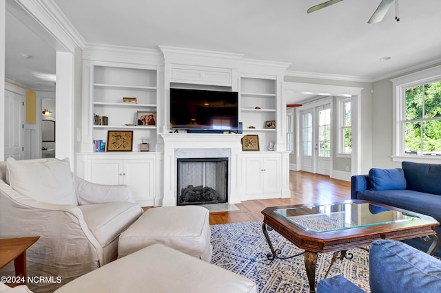 living room with ceiling fan, light wood-type flooring, ornamental molding, and a premium fireplace