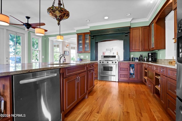 kitchen featuring appliances with stainless steel finishes, light stone counters, light hardwood / wood-style flooring, sink, and decorative light fixtures