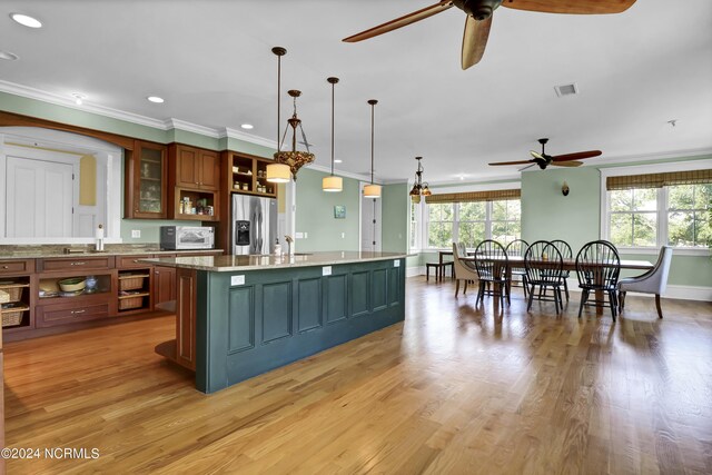 kitchen featuring pendant lighting, a kitchen island with sink, stainless steel fridge with ice dispenser, ceiling fan, and light hardwood / wood-style flooring