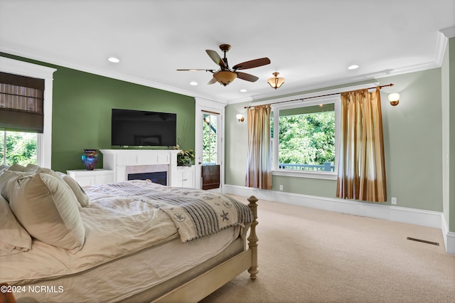 bedroom featuring a tile fireplace, carpet flooring, multiple windows, and ceiling fan