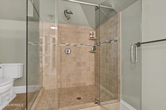 bathroom with a shower with shower door, tile patterned floors, and toilet