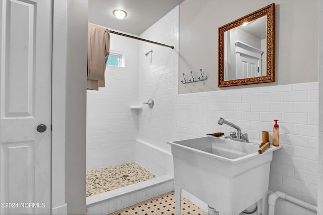 bathroom featuring sink, a tile shower, tile patterned floors, and tile walls