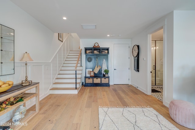 entrance foyer featuring light wood-style flooring, recessed lighting, a wainscoted wall, and stairway