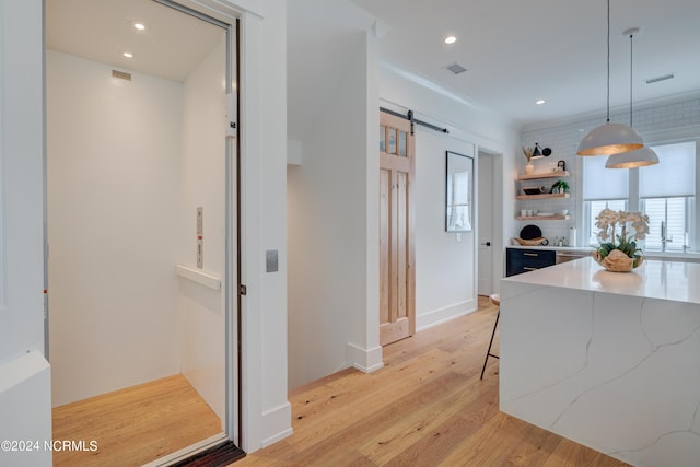 hallway with light wood-style floors, recessed lighting, visible vents, and a barn door