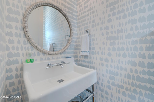 bathroom featuring a sink and wallpapered walls