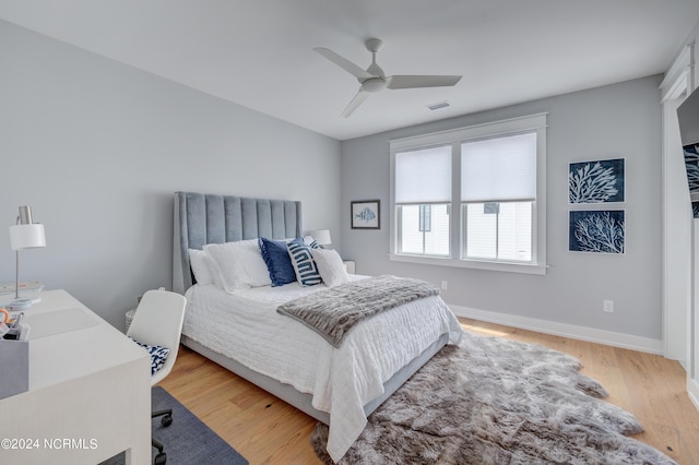 bedroom featuring light wood finished floors, baseboards, visible vents, and ceiling fan