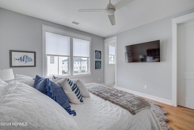 bedroom featuring a ceiling fan, wood finished floors, visible vents, and baseboards