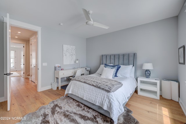 bedroom with light wood-type flooring, a ceiling fan, and baseboards