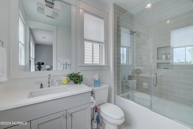 full bath featuring vanity, toilet, and bath / shower combo with glass door