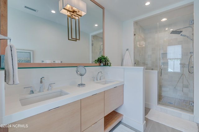 bathroom featuring double vanity, a shower stall, visible vents, and a sink