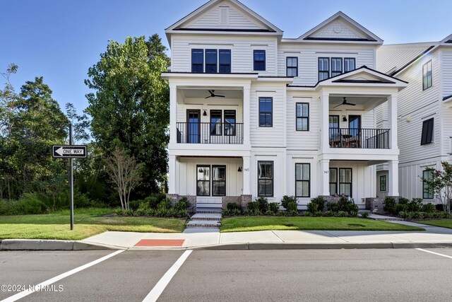 view of front of property with a balcony, ceiling fan, and a front yard