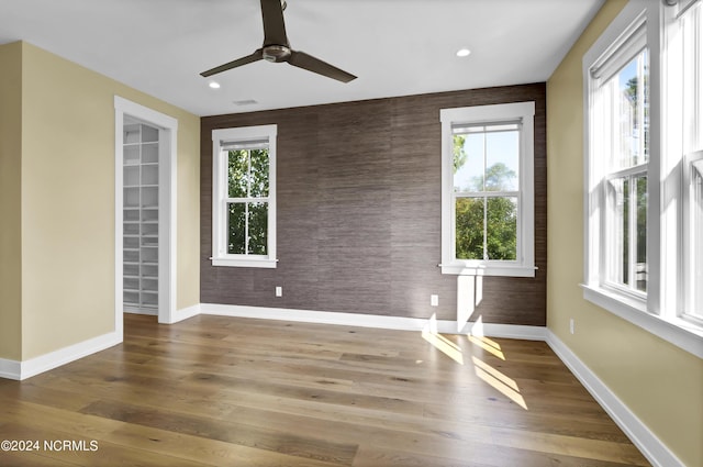 spare room with an accent wall, wood finished floors, and baseboards