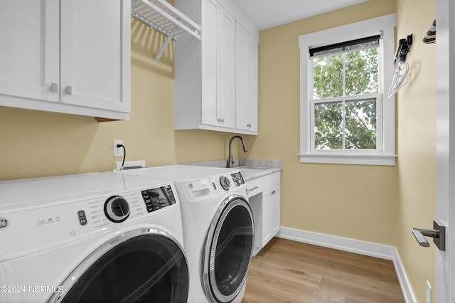 clothes washing area featuring cabinet space, baseboards, light wood-style flooring, separate washer and dryer, and a sink