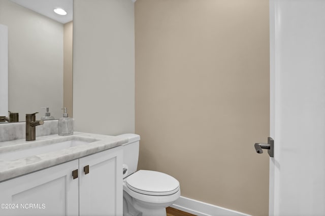 bathroom featuring toilet, baseboards, wood finished floors, and vanity