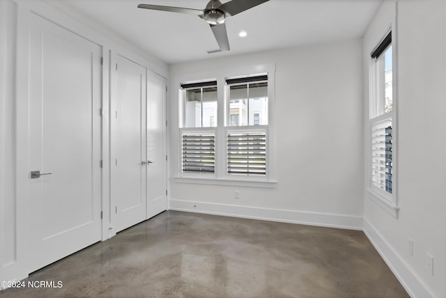 unfurnished bedroom with recessed lighting, multiple windows, finished concrete flooring, and baseboards