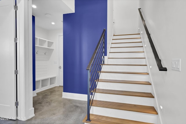 staircase with concrete floors, baseboards, and recessed lighting