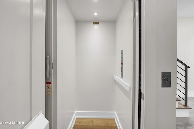 room details featuring elevator, baseboards, and wood finished floors