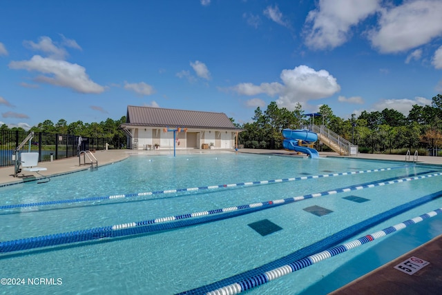 view of pool with a water slide and fence