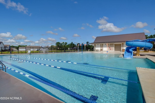 pool with a water slide, fence, and a patio