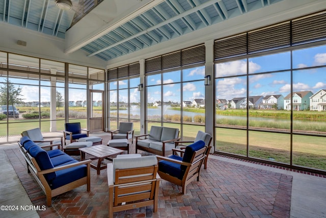 sunroom / solarium featuring a residential view, a water view, and vaulted ceiling with beams