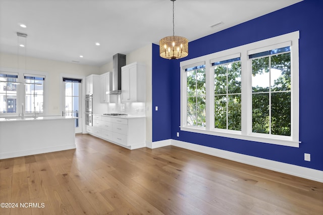 kitchen featuring decorative light fixtures, light countertops, visible vents, white cabinets, and wall chimney exhaust hood