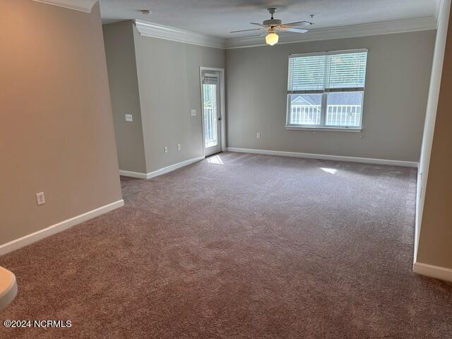 carpeted spare room featuring ornamental molding, ceiling fan, and baseboards