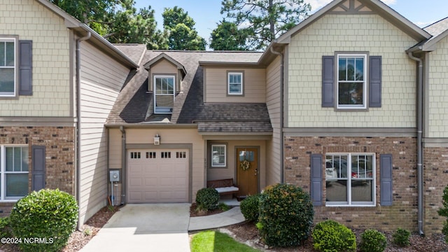 townhome / multi-family property featuring an attached garage, a shingled roof, concrete driveway, and brick siding