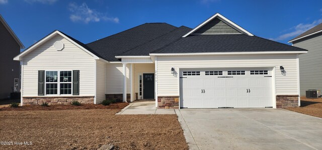 view of front of home with central air condition unit, stone siding, roof with shingles, concrete driveway, and an attached garage