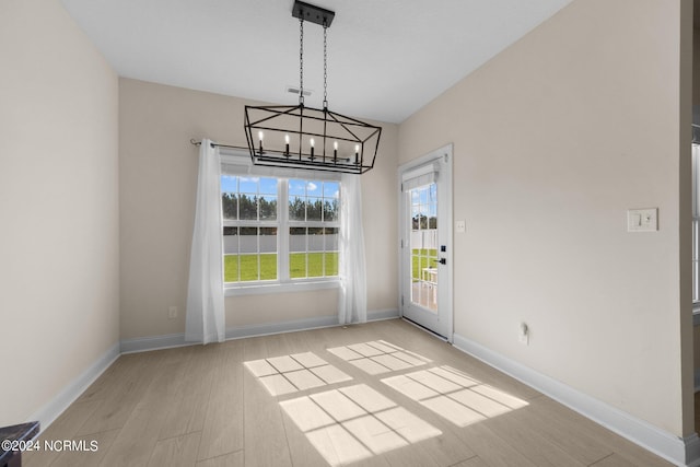 unfurnished dining area featuring a notable chandelier and light hardwood / wood-style floors