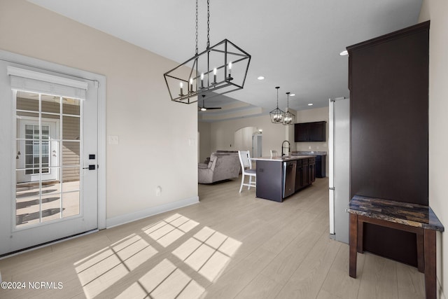 kitchen featuring dark brown cabinets, a kitchen island with sink, light hardwood / wood-style flooring, stainless steel appliances, and decorative light fixtures