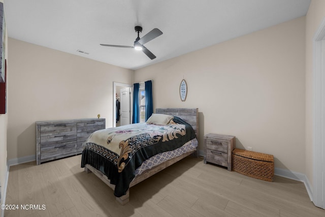 bedroom featuring a spacious closet, light hardwood / wood-style flooring, and ceiling fan