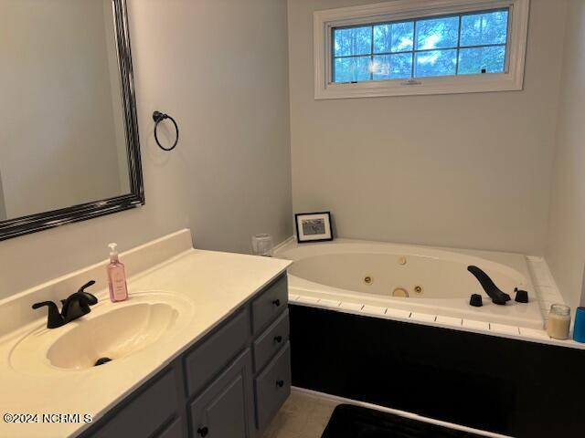 bathroom with vanity and a relaxing tiled tub